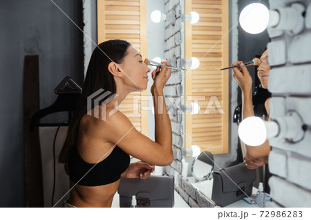 Reflection of young beautiful woman applying her make-up 72986283