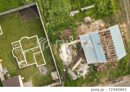 Aerial view of a brick house with wooden roof frame under construction and foundation for a new project. 72990865