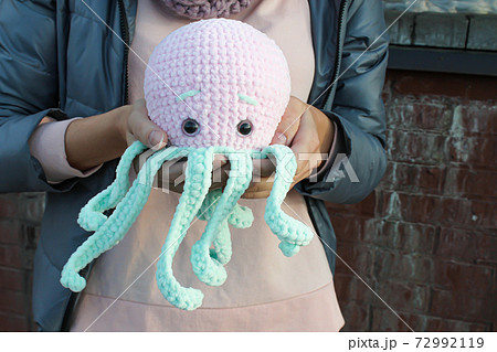Big pink knitted octopus in the hands of the girl Big pink knitted octopus in the hands of the girl 72992119