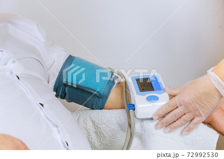 Female doctor with pressure to medical tonometer to measure pressure on the patient arm Female doctor with pressure to medical tonometer to measure pressure on the patient arm 72992530