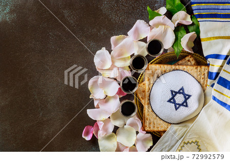 Red kosher wine four glasses of matzah or matza Passover Haggadah on talit and kippa a vintage background Red kosher wine four glasses of matzah or matza Passover Haggadah on talit and kippa a vintage background 72992579