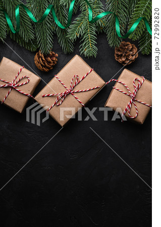 Christmas holidays composition. Green ribbon and giftbox wrapping, fir-tree, pine cones. Copy space Christmas holidays composition. Green ribbon and giftbox wrapping, fir-tree, pine cones. Copy space 72992820