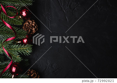 Christmas holidays composition. Red ribbon, ornament and bauble decorations, fir-tree and pine cones. Copy space Christmas holidays composition. Red ribbon, ornament and bauble decorations, fir-tree and pine cones. Copy space 72992821