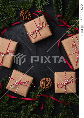 Christmas holidays composition. Red ribbon, ornament and bauble decorations and eco gift boxes. Copy space Christmas holidays composition. Red ribbon, ornament and bauble decorations and eco gift boxes. Copy space 72992822