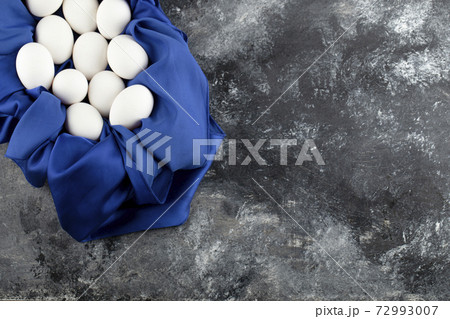 White raw chicken eggs with on a blue tablecloth White raw chicken eggs with on a blue tablecloth 72993007