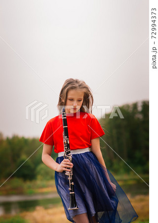 Young attractive girl playing clarinet, ebony in fall park Young attractive girl playing clarinet, ebony in fall park 72994373