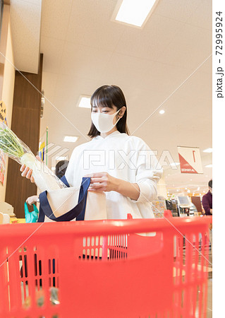スーパーで買い物袋に商品を詰める女性 スーパーで買い物袋に商品を詰める女性 72995924