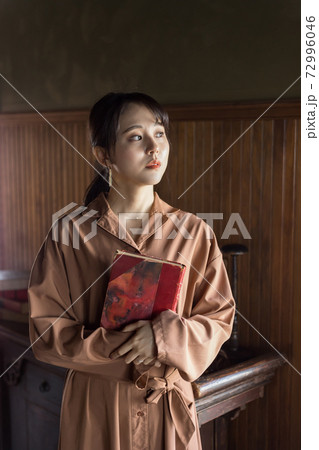 アンティークな部屋で本を抱く女性 72996046