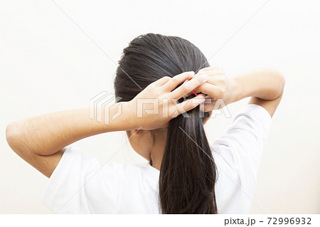髪の毛を結ぶ女の子の写真素材