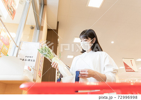 スーパーで買い物袋に商品を詰める女性 72996998