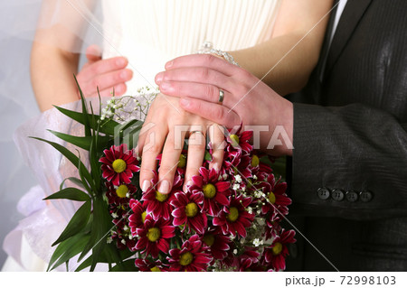 hands of bride and groom near wedding bouquet 72998103