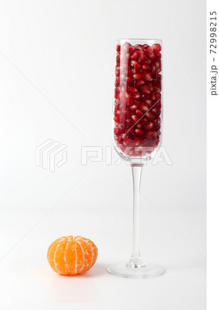 peeled mandarin and a glass of pomegranate on a white background 72998215