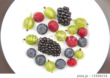 Assorted fresh different berries on a white plate. Assorted fresh different berries on a white plate. 72998258