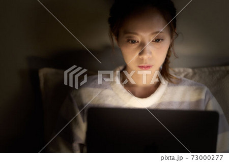 寝室でPCを操作する若い女性 寝室でPCを操作する若い女性 73000277
