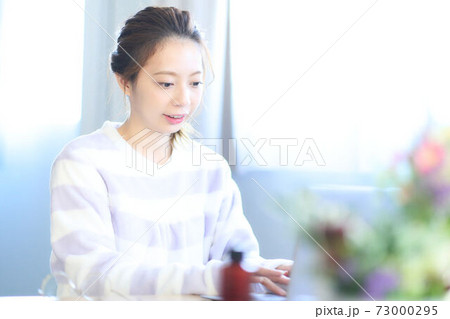 部屋でパソコンを操作する若い女性 部屋でパソコンを操作する若い女性 73000295