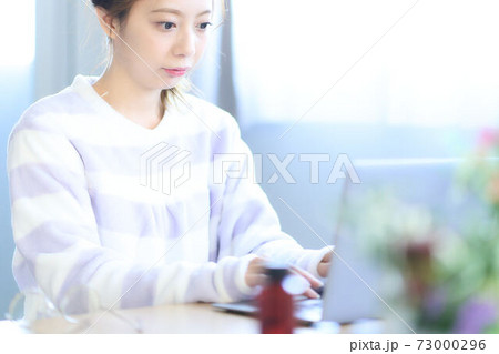 部屋でパソコンを操作する若い女性 73000296