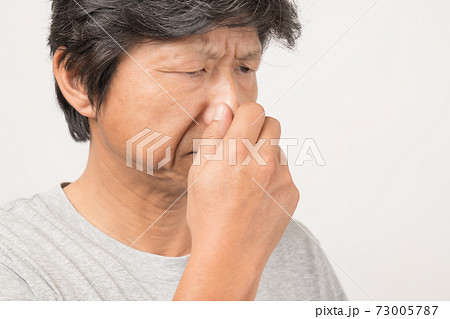 臭い匂いに鼻をつまんでいる中年男性 の写真素材
