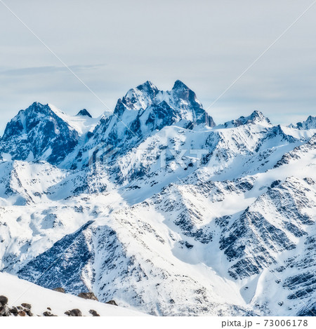 Snowy blue mountains in clouds 73006178