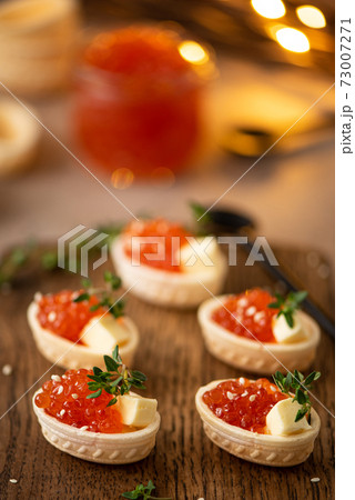 red salted salmon caviar in waffle tartlets on a wooden board 73007271