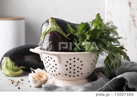 large eggplants with garlic, parsley and dill in a white colander large eggplants with garlic, parsley and dill in a white colander 73007360