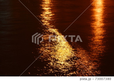 blurry of artificial light pole reflection on canal in night 73007380