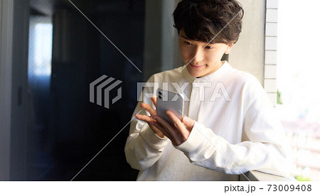 スマホを手にする若い男性 スマホを手にする若い男性 73009408