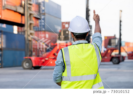 Back of foreman or cargo container worker show thumbs up to other co-worker who control crane truck  73010152