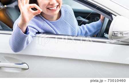 車の運転席でokマークをする若い女性の写真素材