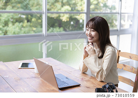 窓際でパソコン作業をする20代女性 73010559
