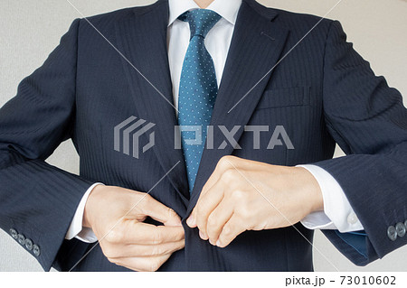 スーツのジャケットを着てボタンをとめるビジネスマンの写真素材