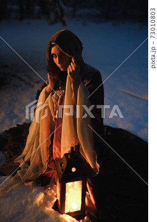 Fantasy night shot of young woman sitting with vintage lantern looking at you. Medieval fairytale concept Fantasy night shot of young woman sitting with vintage lantern looking at you. Medieval fairytale concept 73010803