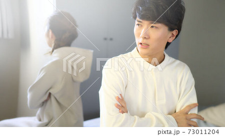 ベッドの上で背を向けて座る男女 73011204