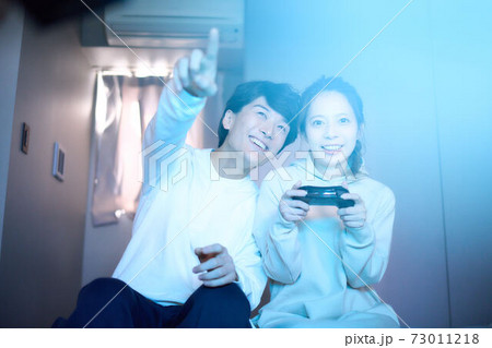 部屋でテレビゲームを楽しむ若い男女 73011218