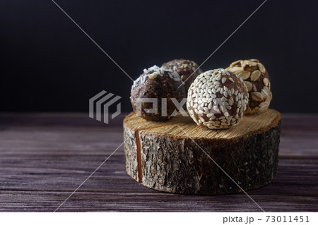 Raw vegan dessert energy balls or raw vegan candy with nuts and dried fruits on wooden background. Sugar free. Raw vegan dessert energy balls or raw vegan candy with nuts and dried fruits on wooden background. Sugar free. 73011451