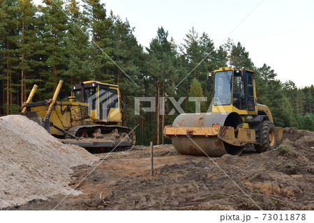 Dozer and Vibro Roller Soil Compactor at road construction and bridge projects in forest area. 73011878