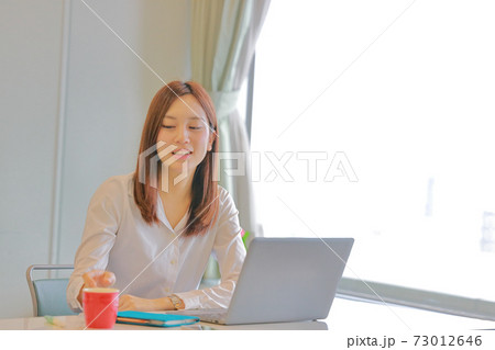 コーヒーカップに手を伸ばすビジネスウーマン コーヒーカップに手を伸ばすビジネスウーマン 73012646