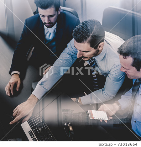Businessmen trading stocks. Stock traders looking at graphs, indexes and numbers on multiple computer screens. Colleagues in discussion in traders office. Business success concept Businessmen trading stocks. Stock traders looking at graphs, indexes and numbers on multiple computer screens. Colleagues in discussion in traders office. Business success concept 73013664