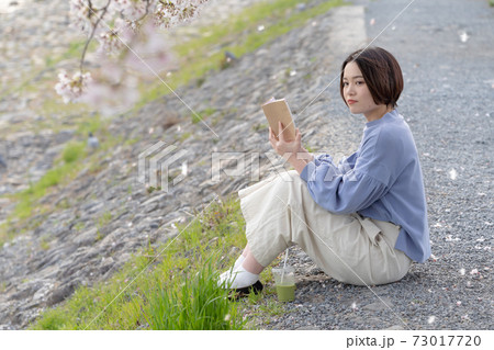 春の時期、公園で読書を楽しむ女性 春の時期、公園で読書を楽しむ女性 73017720