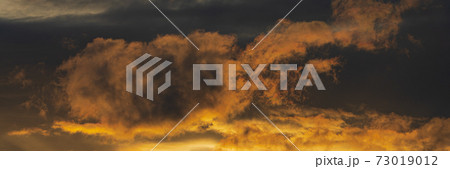 Panoramic view of dramatic clouds illuminated rising of sun in sky to change weather. Natural meteorology background. Majestic cloudscape 73019012