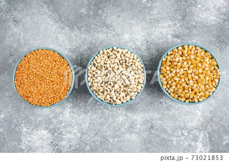 Assortment of raw beans, corn kernels and red lentils on marble background Assortment of raw beans, corn kernels and red lentils on marble background 73021853