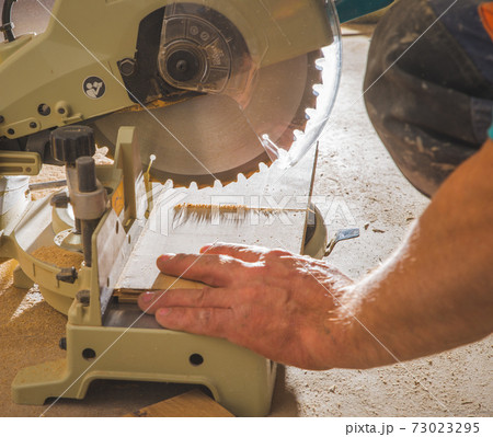 workman sawing a piece of wood workman sawing a piece of wood 73023295