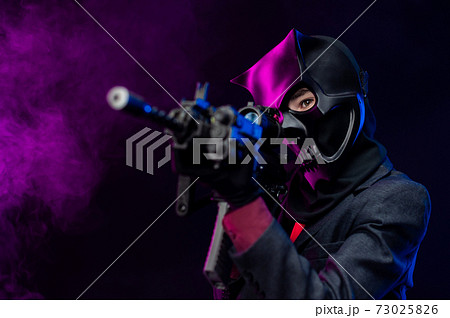 a man wearing a demon skull mask in a leather cloak with an airsoft gun a man wearing a demon skull mask in a leather cloak with an airsoft gun 73025826