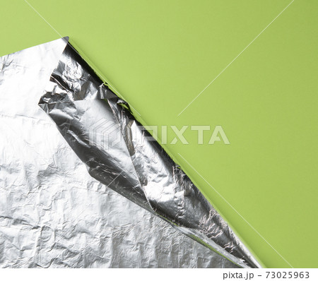 rolled sheet of foil on a green background, the corner is folded rolled sheet of foil on a green background, the corner is folded 73025963