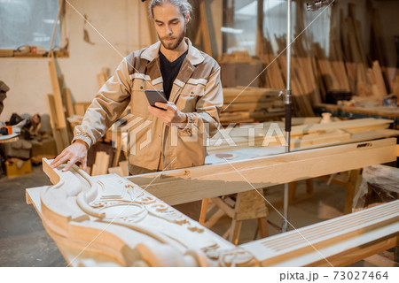 Carpenter working on smart phone at the carpentry Carpenter working on smart phone at the carpentry 73027464