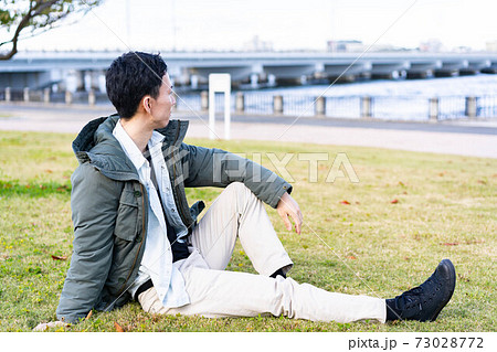 公園の芝生でくつろぐ男性 73028772