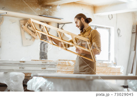 Carpenter with window frame at the workshop Carpenter with window frame at the workshop 73029045