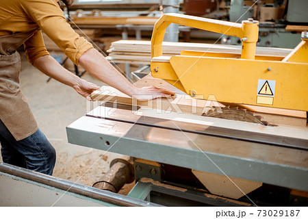 Carpenter sawing wooden planks 73029187