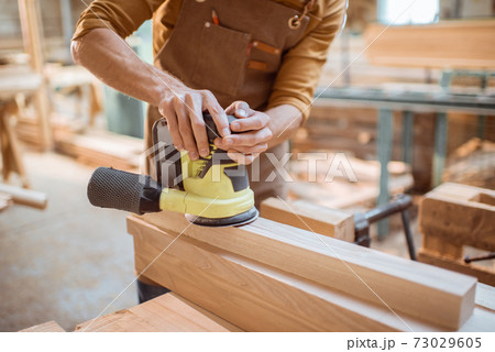 Carpenter grinding wooden bar 73029605