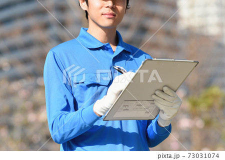 メモを取る作業服姿の男性 73031074