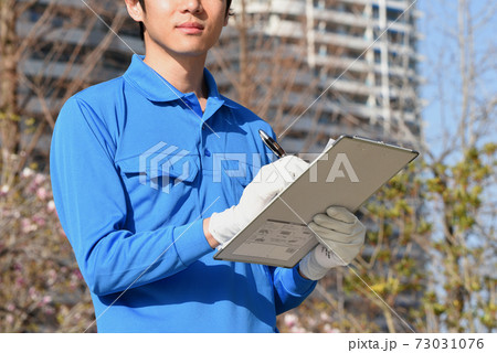 メモを取る作業服姿の男性 73031076